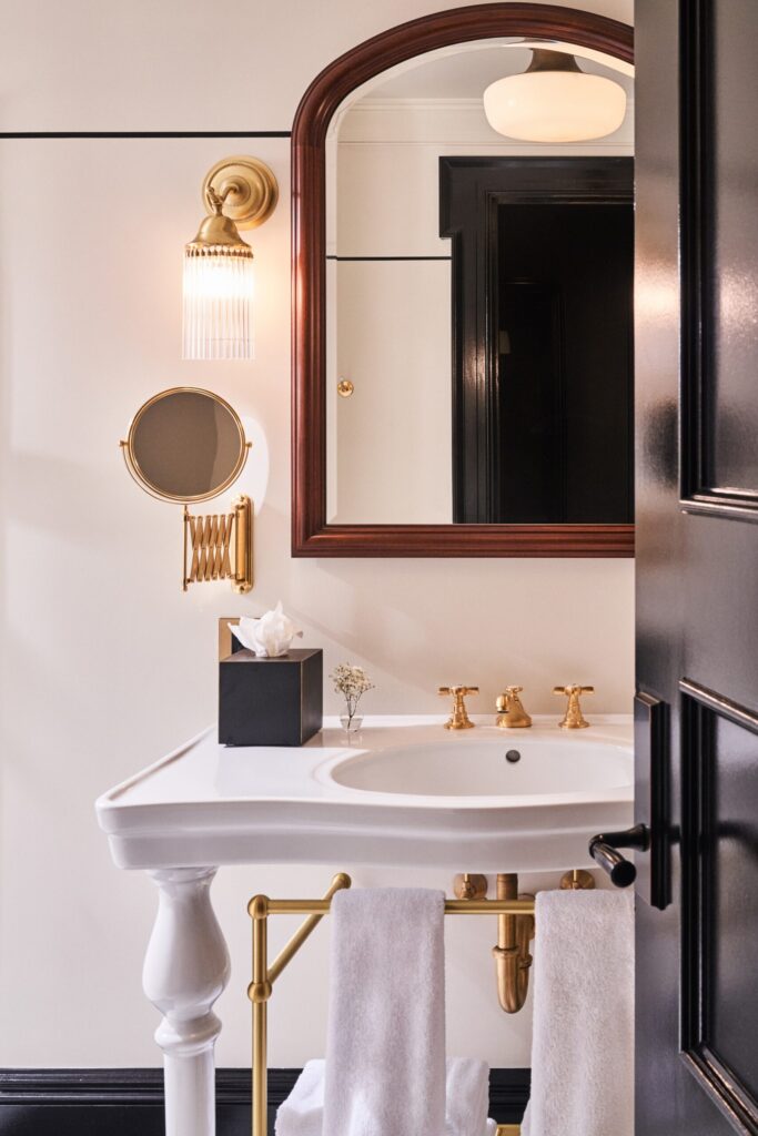 Bathroom sink and mirror at The Twenty Two New York, featuring neatly arranged towels and elegant design details.