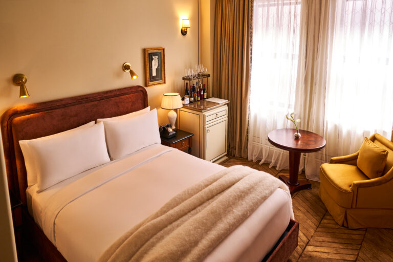 Overhead view of the Classic Room at The Twenty Two New York, featuring a king-size bed, a small coffee table, and a single chair in an elegant setting.